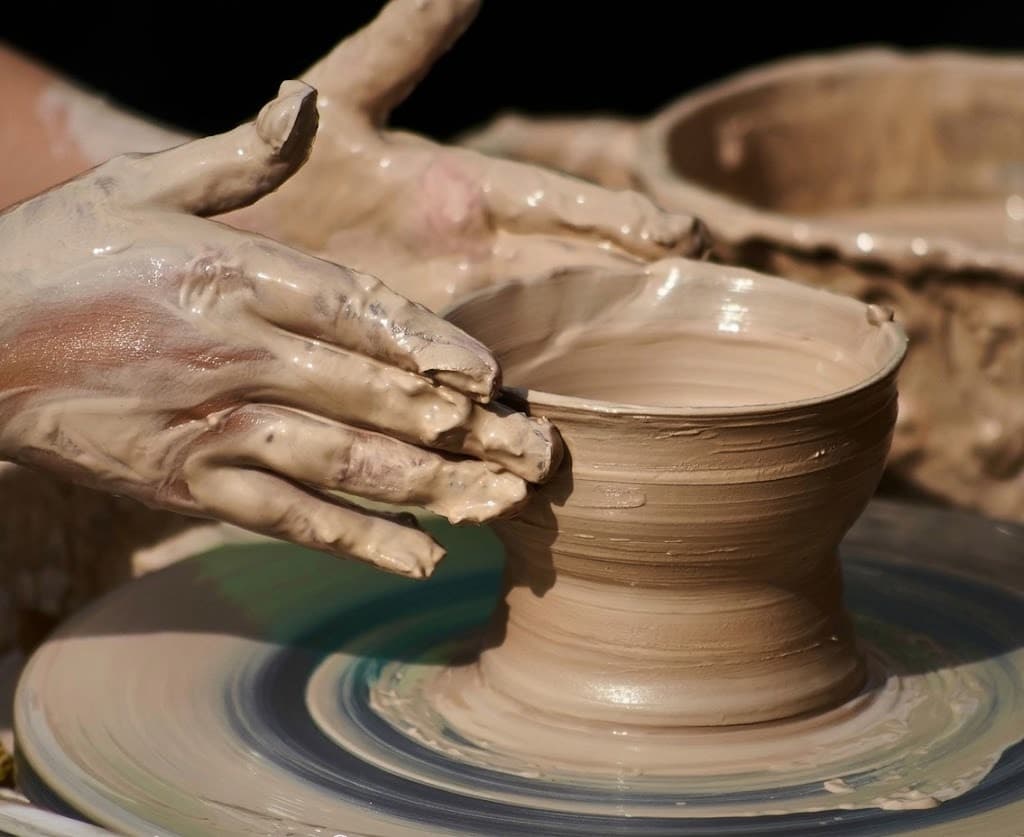 Potter's hands shaping a clay bowl on a pottery wheel